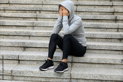 Woman crying and sitting alone on city stairs © lzf