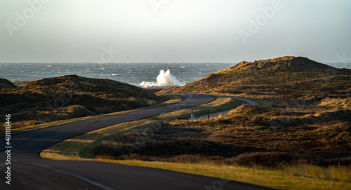 Stormy day in Denmark in Norre vorupor, view of a country road and North Sea with big waves