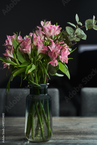 a bouquet of pink alstroemerias on a table in a dark interior photo