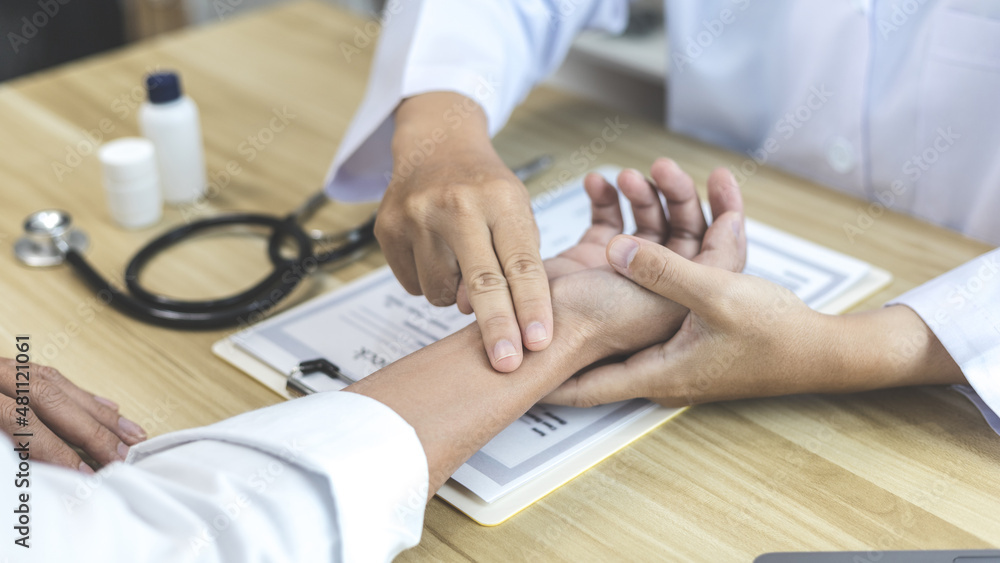 Medical professional measures the pulse of a male patient's wrist to check his heart rate in the hospital's examination room, Doctor checking patient health, Initial symptom check. Medical professional measures the pulse of a male patient's wrist to check his heart rate in the hospital's examination room, Doctor checking patient health, Initial symptom check.