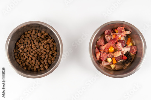 Two bowls with dog food, processed and natural stuff. Comparing of different kind of diet. The process of changing from one system to another. White background, copy space.