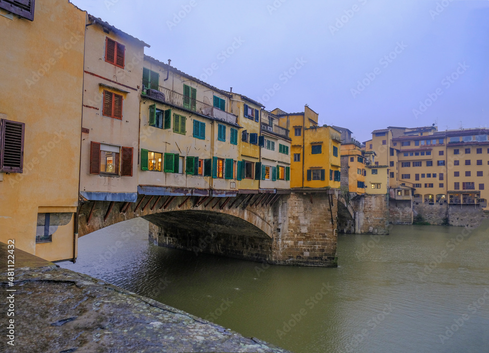 Florence, Italy: View on the Florence Ponte Vecchio with colorful stores on a rainy day across river Arno and dramatic gray sky	
