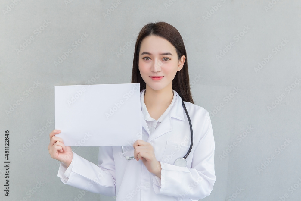 Asian woman doctor who wears medical coat holds and shows white paper to present something in healthcare concept. Asian woman doctor who wears medical coat holds and shows white paper to present something in healthcare concept.