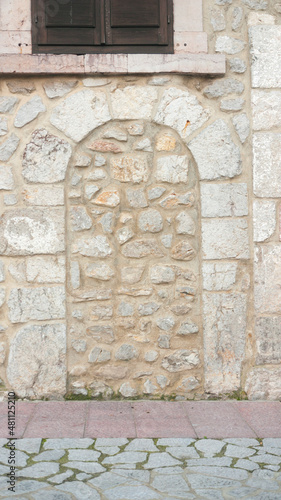 Puerta en arco tapiada con piedra en fachada de piedra