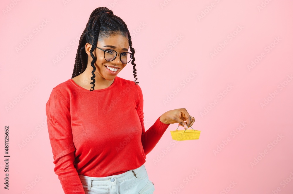 african american girl with shopping cart on pink background. The concept of profitable sales or purchases. african american girl with shopping cart on pink background. The concept of profitable sales or purchases.