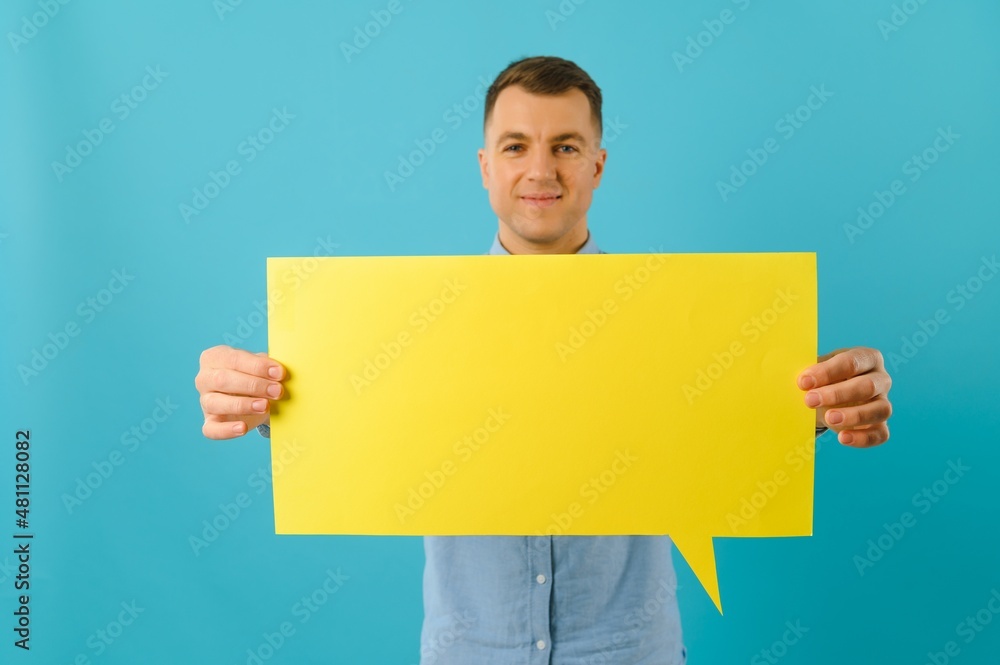 Joyful Caucasian man demonstrating blank placard on blue studio background, mockup for design Joyful Caucasian man demonstrating blank placard on blue studio background, mockup for design