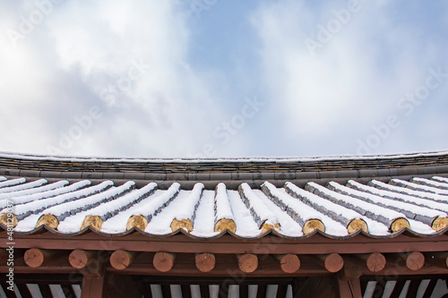 Korean New Year's Day image. Close-up of the tile image covered with snow in the sky background. Giwa, Korean Traditional Roof Tile Used for Building a Hanok, a Korean-style House