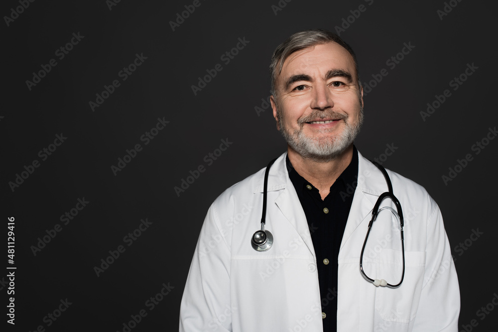 smiling bearded doctor with stethoscope looking at camera isolated on black. smiling bearded doctor with stethoscope looking at camera isolated on black.