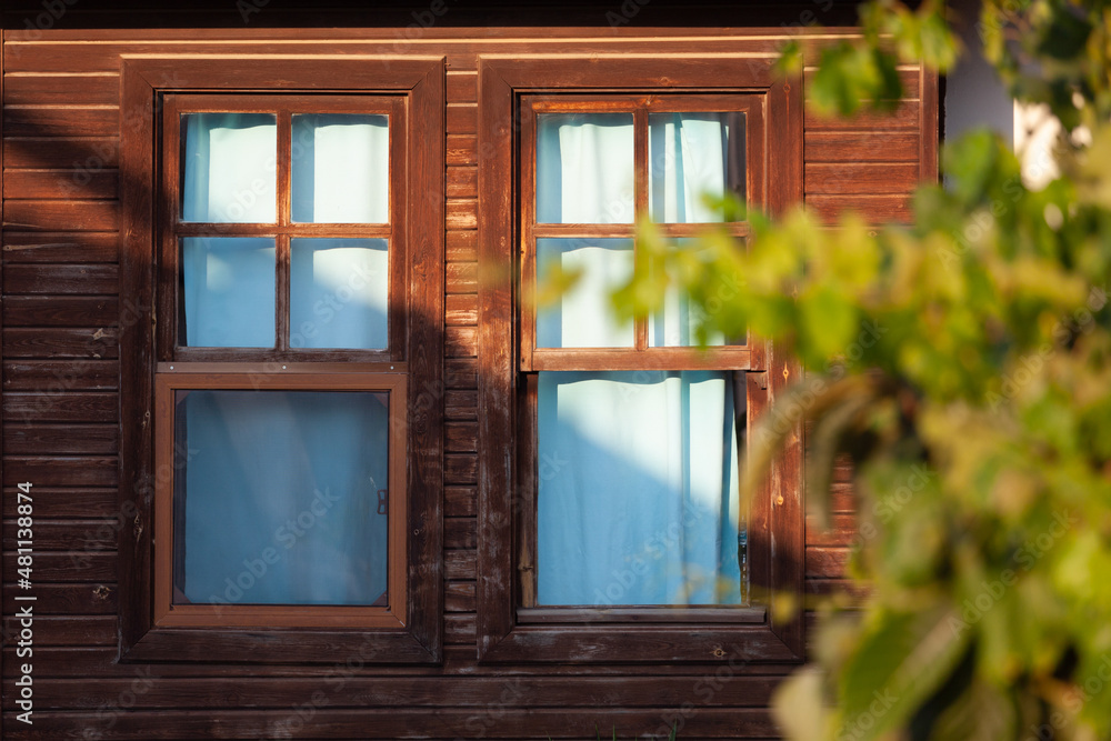 Example of wooden architecture visible behind branches, two windows Example of wooden architecture visible behind branches, two windows