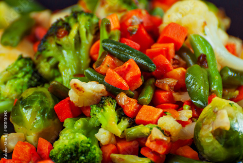 Mix of vegetables close up. Salad of various chopped vegetables. Roasted cabbage, carrots, broccoli, peas on a plate.