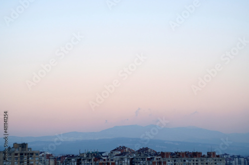sunset over the city and mountains on the horizon with sky gradient from purple to blue 