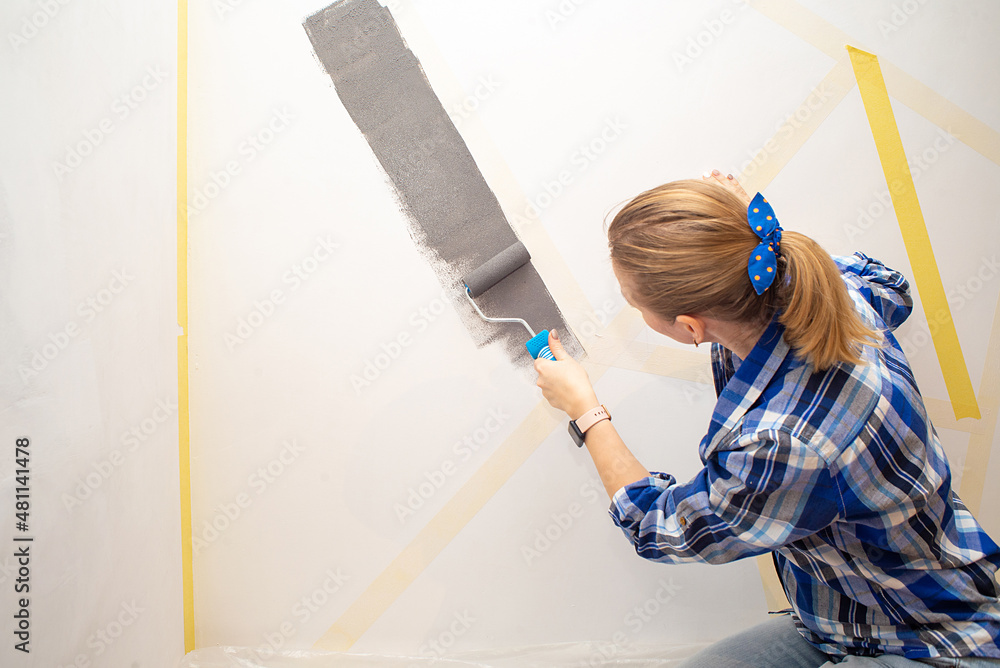 Young happy woman painting interior wall with paint roller in new house, Home decoration concept Young happy woman painting interior wall with paint roller in new house, Home decoration concept