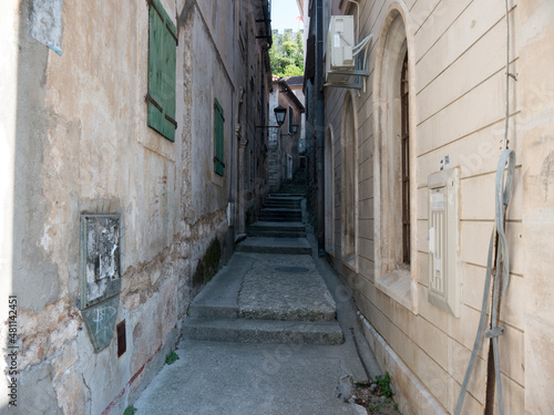Narrow path in old house walls with stone stairs  windows and iron lamp