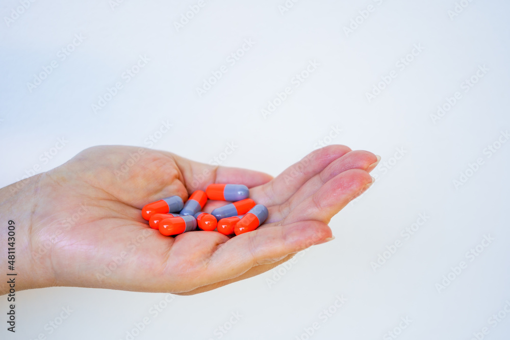 Female hand holding capsule tablet or medication pill on white background Female hand holding capsule tablet or medication pill on white background
