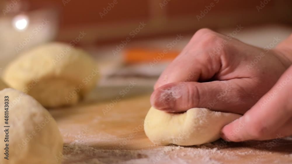 Baker is stirring yeast dough on the board with flour. Baking at home Baker is stirring yeast dough on the board with flour. Baking at home