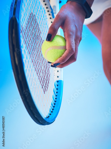 Her service game is on point. Cropped shot of an unrecognizable young female tennis player getting ready to serve against a blue background. photo