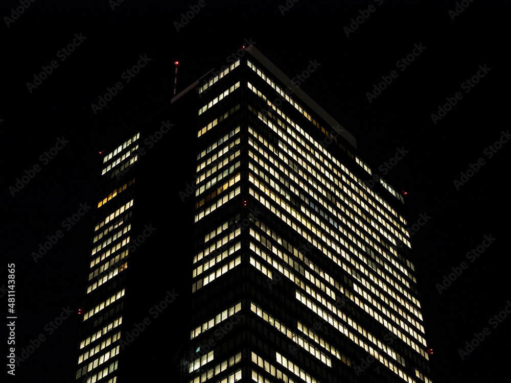 Fototapeta premium 夜のオフィスビル。明かりの灯る窓。