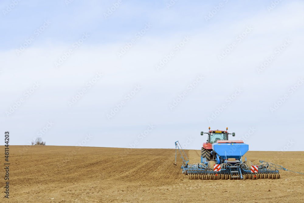 Fototapeta premium A tractor sows cereal crops with a precision seeder in the field.