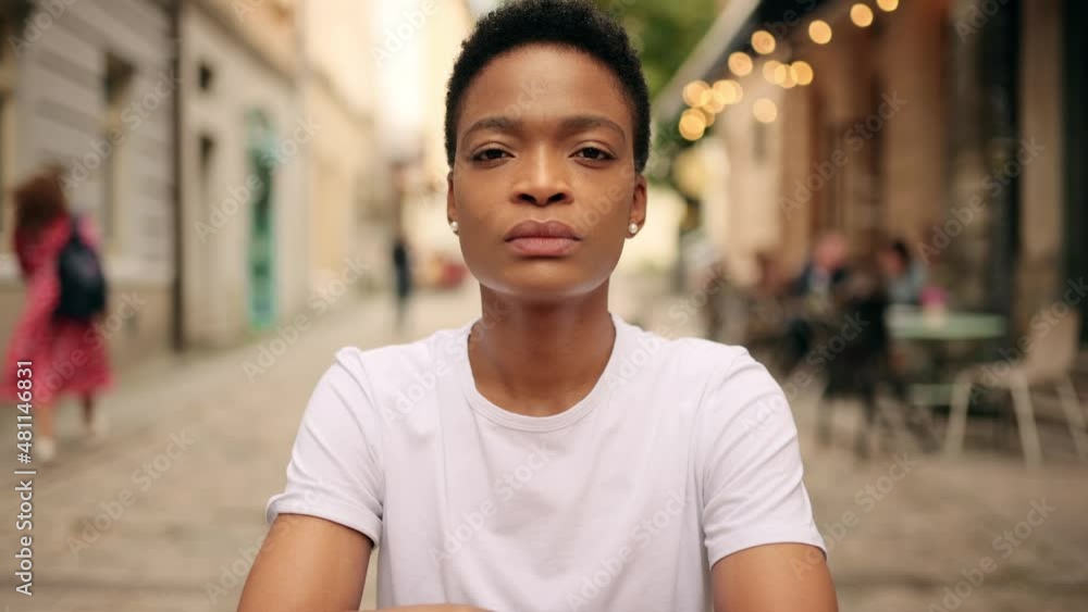 Amazing african american lady sitting cozy on chair in the middle of the city street and looking at the camera Amazing african american lady sitting cozy on chair in the middle of the city street and looking at the camera