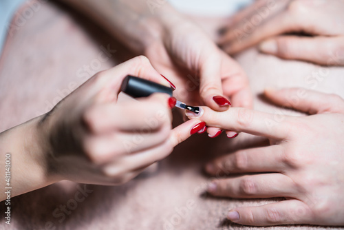 Close up image of manicure process  manicurist applying  gel nail polish on female fingernails. Focus on fingernail.