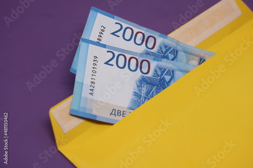 Banknotes in a yellow envelope on a purple background. Bribery concept. Salary in envelopes. Financial fraud. photo