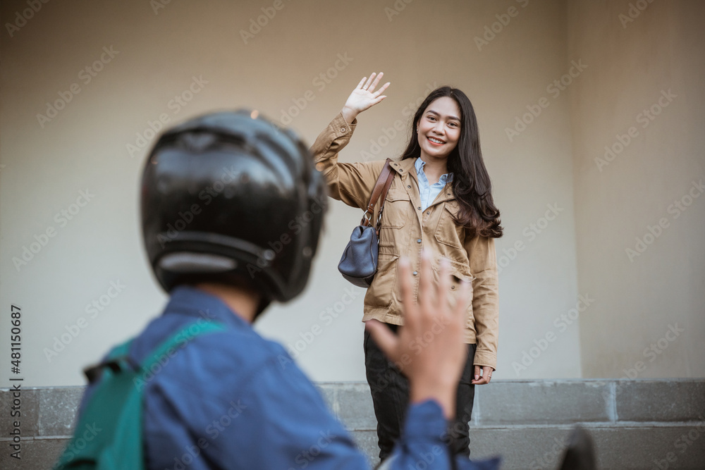 Smiling woman happily waving to people riding motorbikes