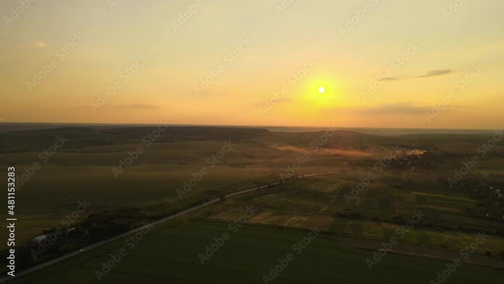 Aerial view of intercity road with fast driving cars between farmland fields at sunset. Top view from drone of highway traffic in evening Aerial view of intercity road with fast driving cars between farmland fields at sunset. Top view from drone of highway traffic in evening