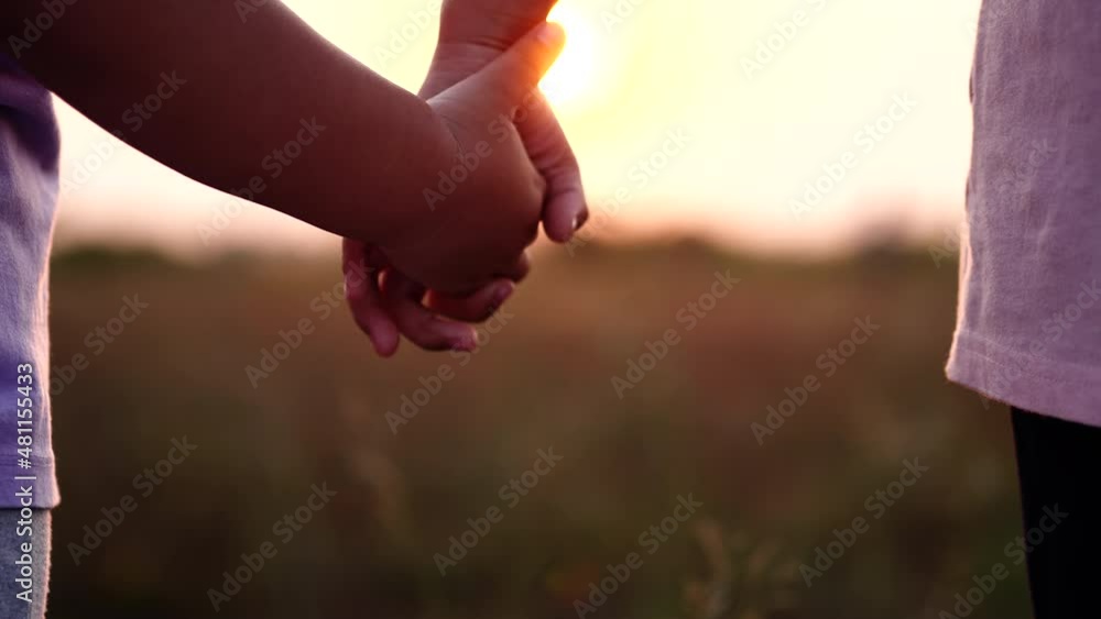 Happy Family Concept. Close-up two little sisters hands joining and holding hand together run across the field with sunset sunlight flare in beautiful natural background, Slow motion. Happy Family Concept. Close-up two little sisters hands joining and holding hand together run across the field with sunset sunlight flare in beautiful natural background, Slow motion.