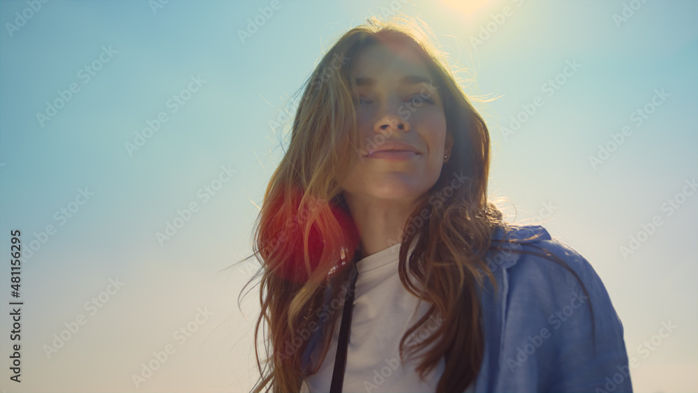 Portrait of beautiful woman in sunlight. Blue-eyed girl face in sunbeams outdoor