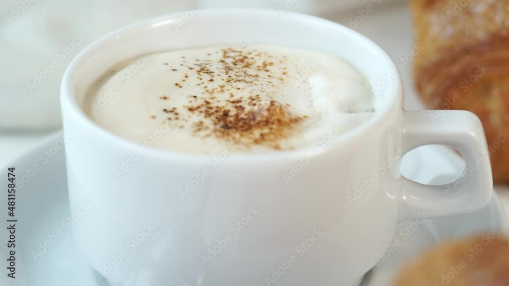 Camera movement on fresh hot cappuccino coffee with creamy foam on background of freshly baked french croissants. Breakfast Camera movement on fresh hot cappuccino coffee with creamy foam on background of freshly baked french croissants. Breakfast