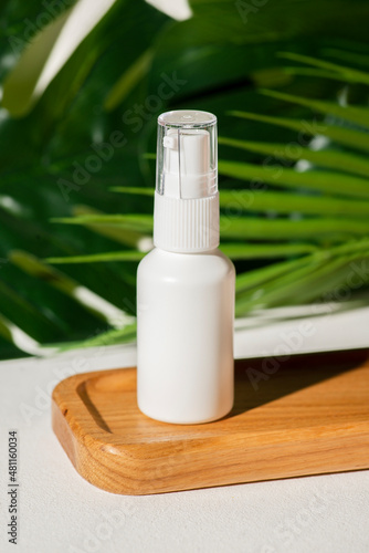 Cuadro en lienzo Plastic white tube for lotion with pomp on wooden plate against the background of palm leaves