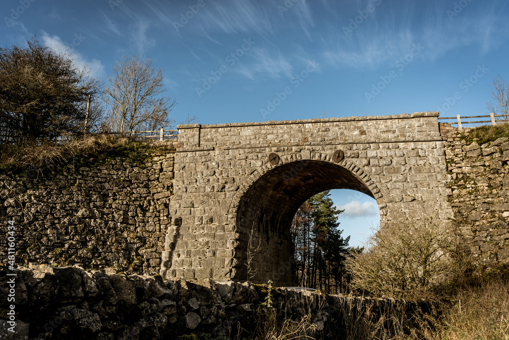 old stone bridge under blue skies and clouds