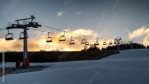 Ski resort image with empty chair lift. Sky at background. Ski-lift silhouette.