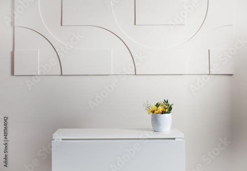Puste wnętrze - biała ściana, biały stół z rośliną w białej doniczce