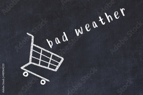 Chalk drawing of shopping cart and word bad weather on black chalboard. Concept of globalization and mass consuming