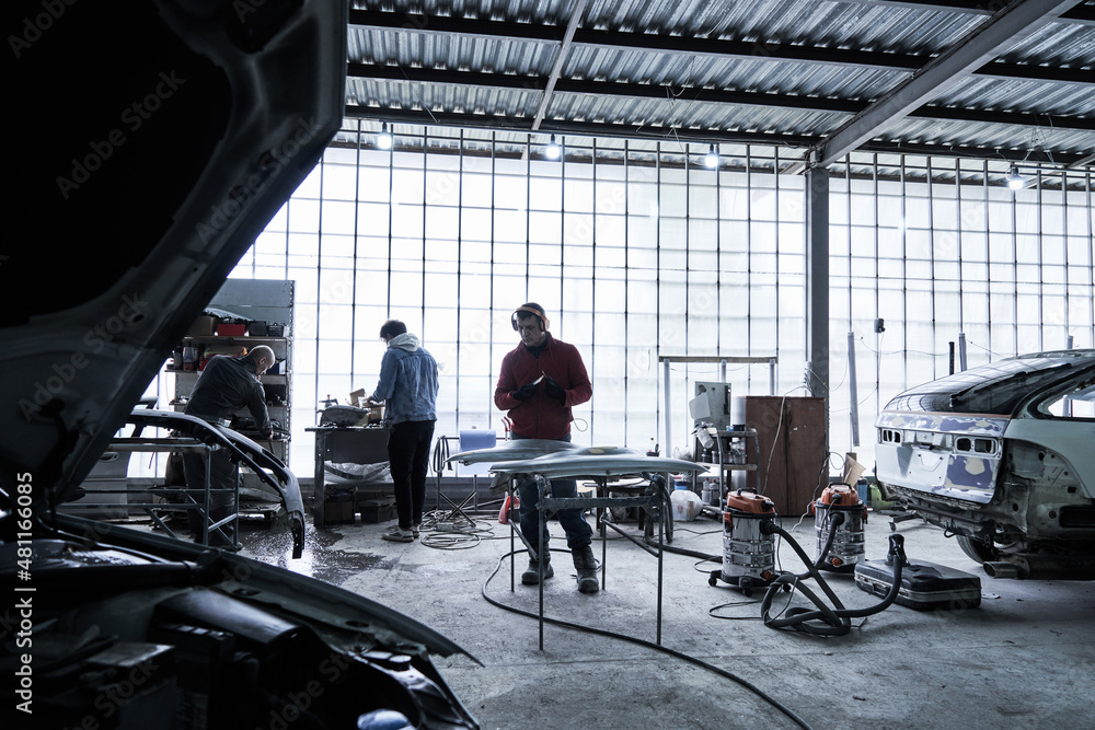 Obraz premium Car service worker repairs restores car