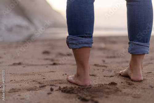 woman feet in sand with jeans