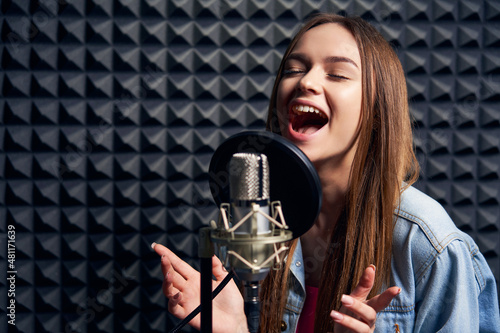 Teen girl in recording studio with mic over acoustic absorber panel background