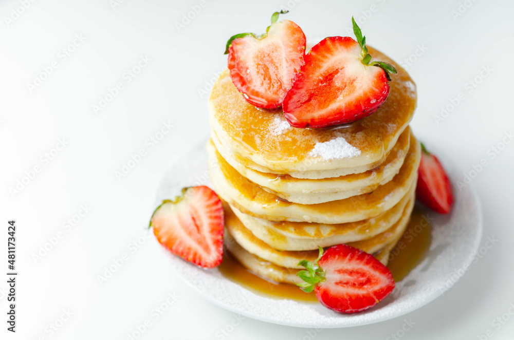 Delicious pancakes stacked with fresh sweet strawberries, topped with maple syrup Delicious pancakes stacked with fresh sweet strawberries, topped with maple syrup