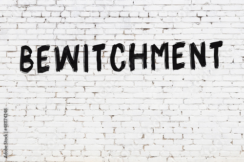 Inscription bewitchment painted on white brick wall