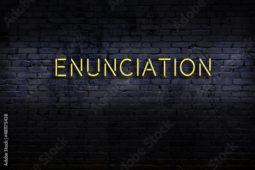 Night view of neon sign on brick wall with inscription enunciation photo