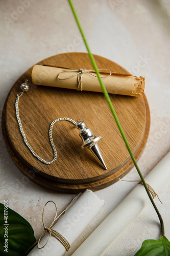 Silver divination pendulum on a wooden board