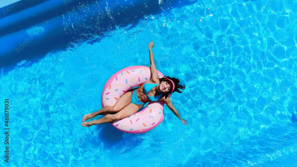 top view of cheerful woman swimming on swim ring in pool