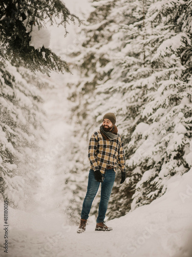 bearded man in a hat walking winter forest