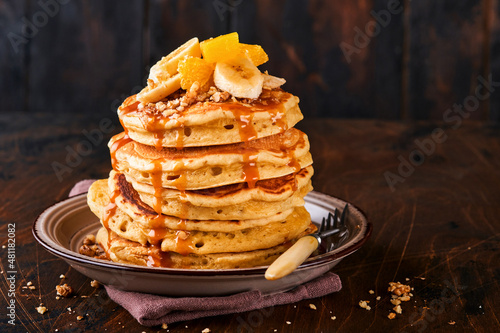 Pancakes. Homemade fluffy pancake with banana, walnut and caramel for breakfast on dark wooden background. Delicious pancakes for traditional American breakfast. Selective focus. Mock up.