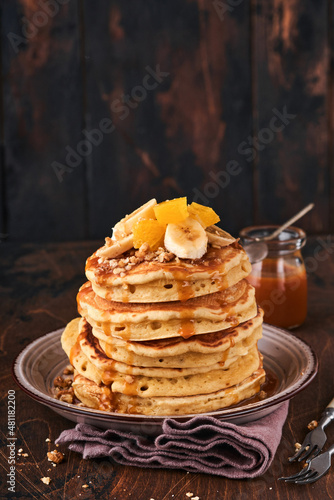 Pancakes. Homemade fluffy pancake with banana, walnut and caramel for breakfast on dark wooden background. Delicious pancakes for traditional American breakfast. Selective focus. Mock up.