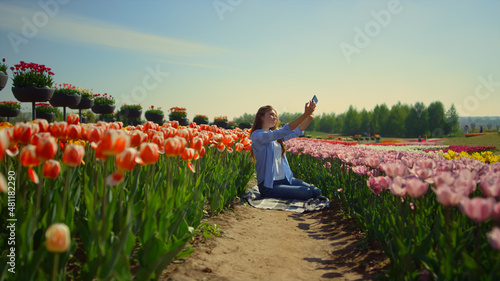 Bright tulip field and young woman making selfie in flower background #481182290