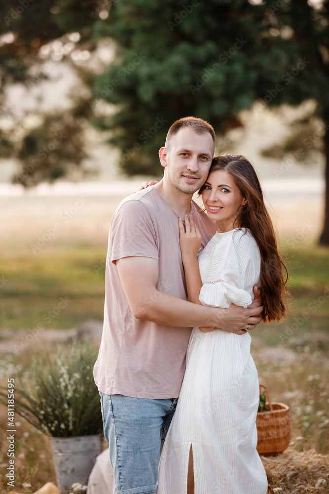 Fototapeta premium young happy couple in love hugging on nature. Man and woman hugging, sunlight in summer meadow. Happy family in the evening sun light. The concept holiday. valentine's day