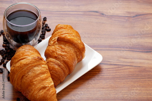 Coffee, freshly baked croissants with a crispy crust on a wooden table