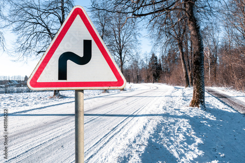 Warning road sign indicating a double bend in wintry conditions